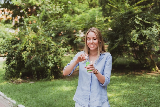 Young woman blowing bubbles in the park and having fun