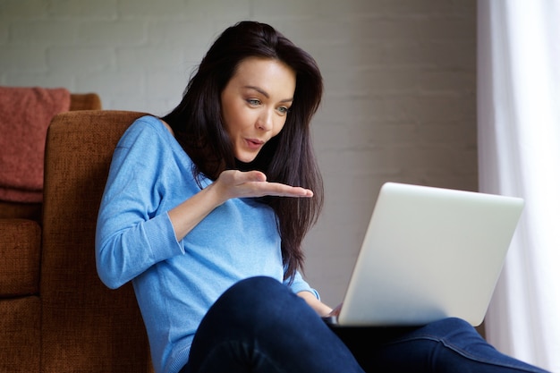 Young woman blowing a kiss at laptop during a video chat 