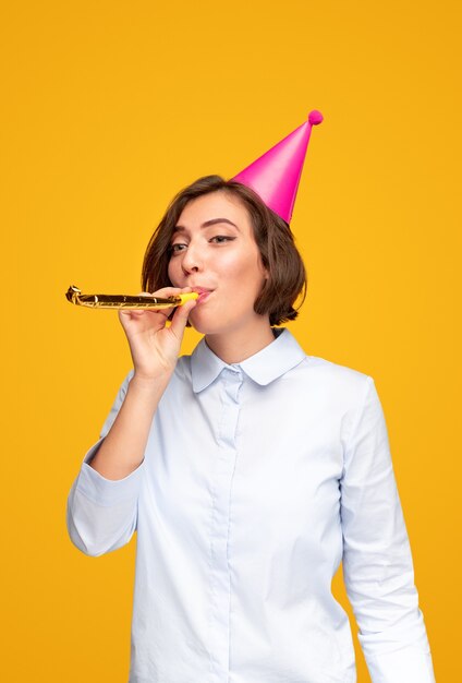 Young woman blowing noisemaker during birthday celebration