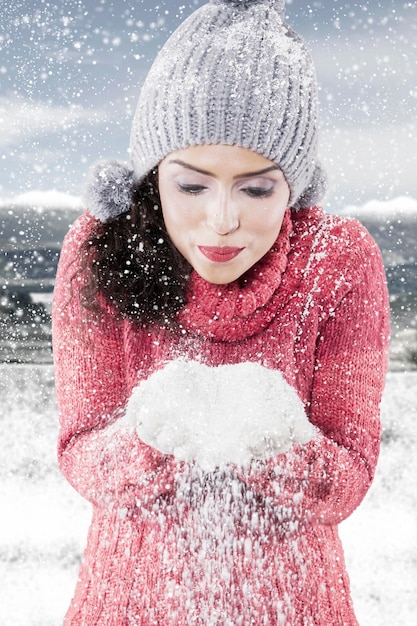 Молодая женщина сдувает снег с рук