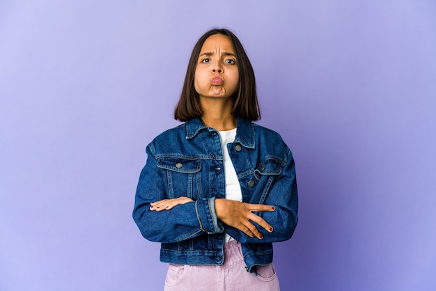 Young woman blows cheeks, has tired expression