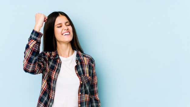 Young woman on blue celebrating a victory, passion and enthusiasm, happy expression.