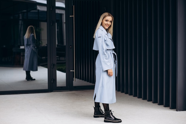 Young woman in blue coat by the office building