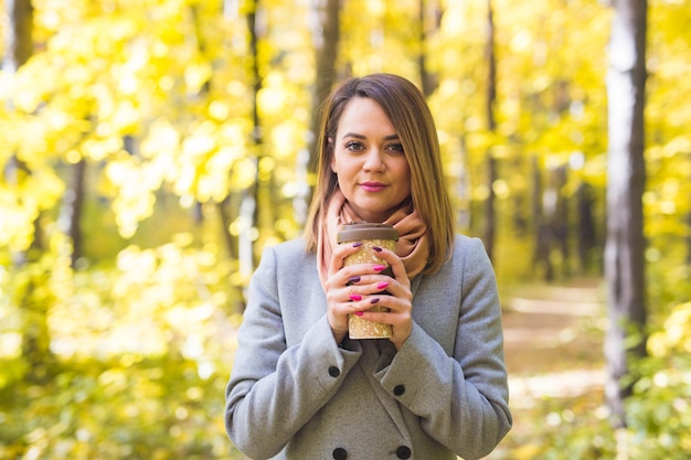 Young woman in a blue coat standing in the park