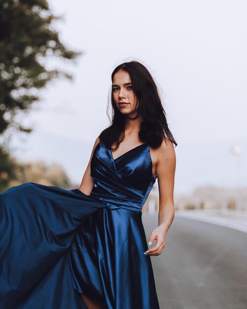 Photo young woman in blue dress standing on road