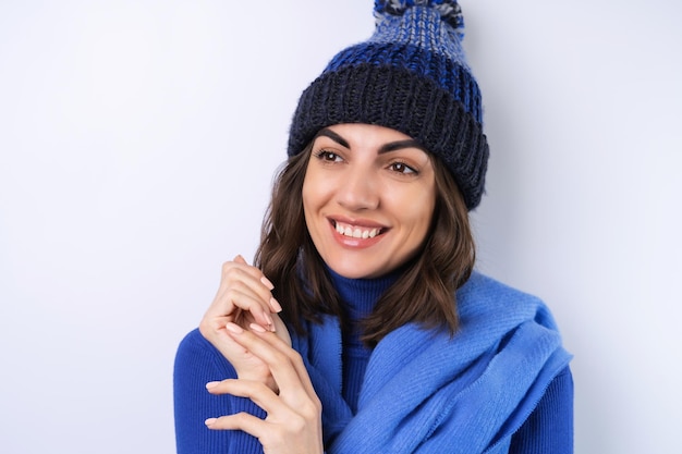 Young woman in a blue golf turtleneck hat and scarf on a white background cheery in a good mood