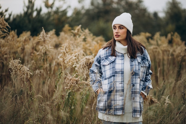 Young woman in blue jacket and white hat walking in autumnal forest