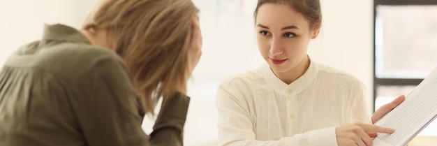 The young woman boss in the office shows a mistake to a colleague in the documents a closeup