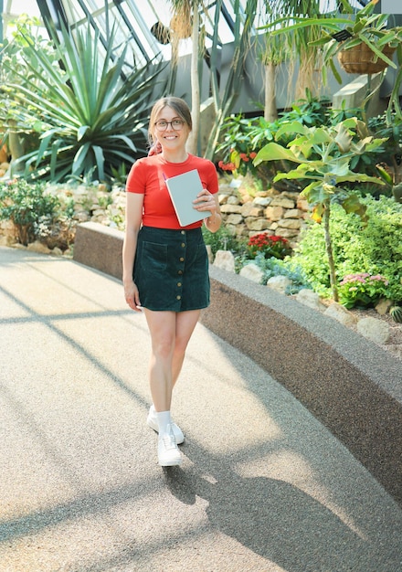 Young woman botanist student walking in a botanical garden