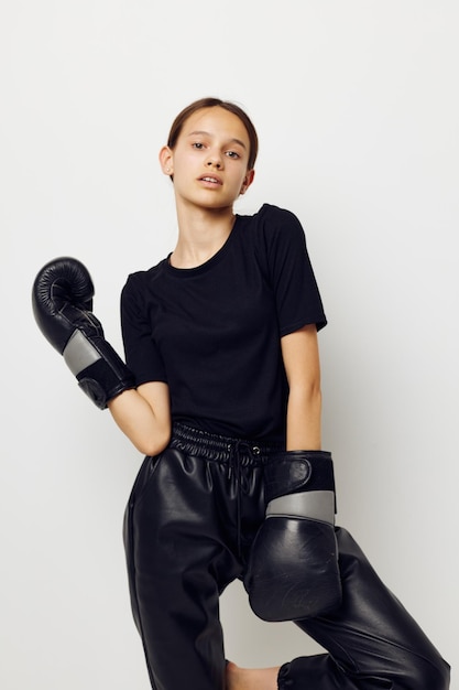 Young woman in boxing gloves in black pants and a Tshirt light background