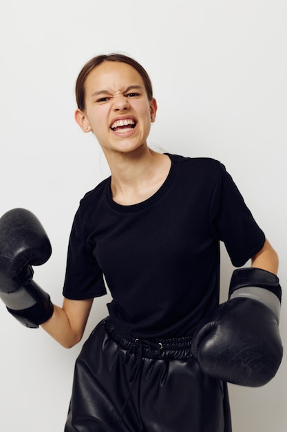 Молодая женщина в боксерских перчатках в черных брюках и светлом фоне футболки