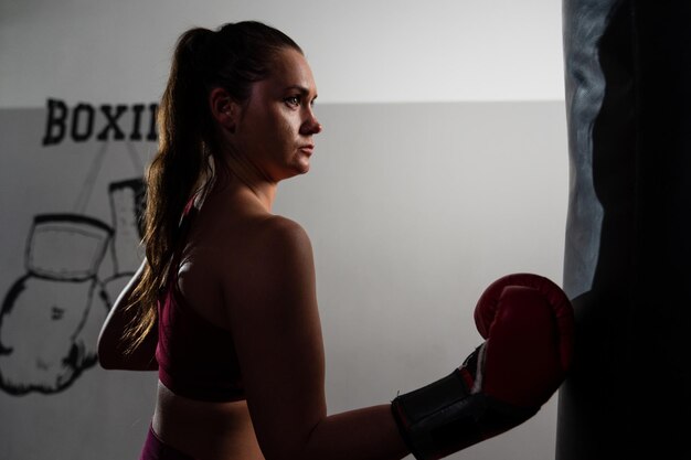 Photo a young woman in boxing gloves practises punching a pear