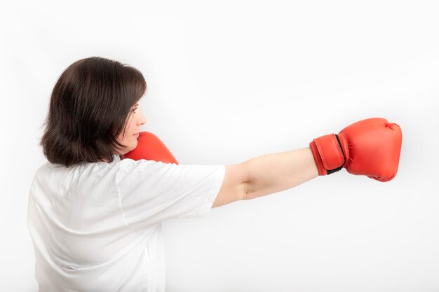 Young woman in boxing gloves on white background. concept of protection of womens rights. side view