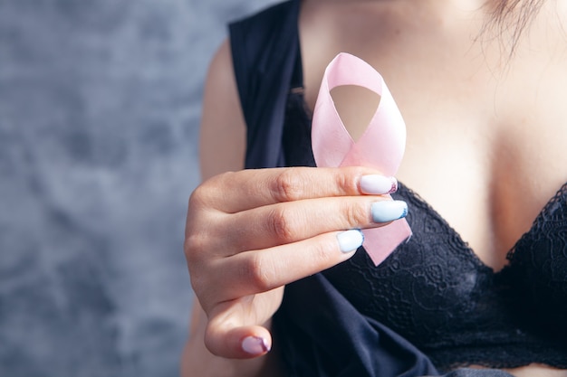 Young woman in bras holds a pink ribbon. mammary cancer