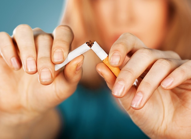 Young woman breaking cigarette  on background