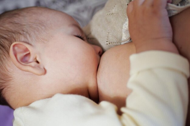 Young woman breastfeeding her baby at home close up