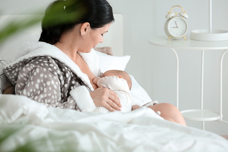 Photo 自宅で赤ちゃんを母乳で育てる若い女性