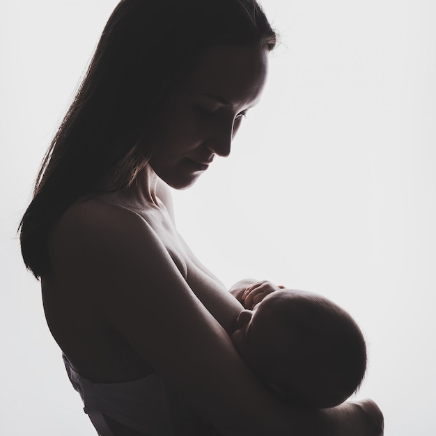 Молодая женщина кормит грудью своего новорожденного ребенка