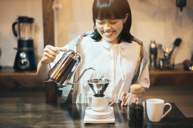 Молодая женщина, заваривающая кофе капающей из руки в тихо освещенном месте