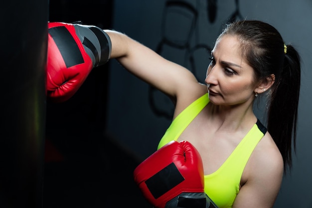 A young woman in a bright tracksuit practices punches on a punching bag