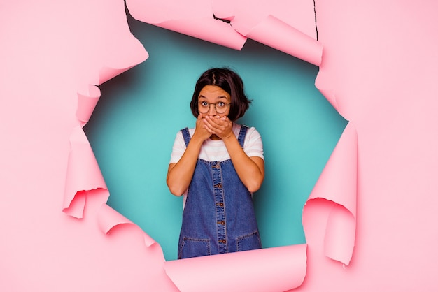 Young woman behind a broken wall covering her mouth