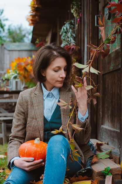 young Woman in a brown warm jacket and jeans on a rustic background.