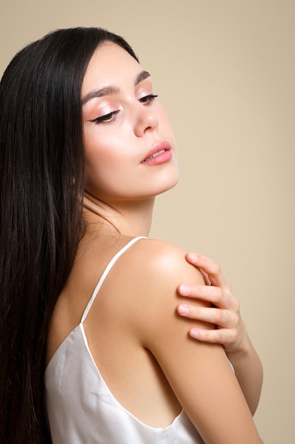 Young woman brunette girl on a beige background