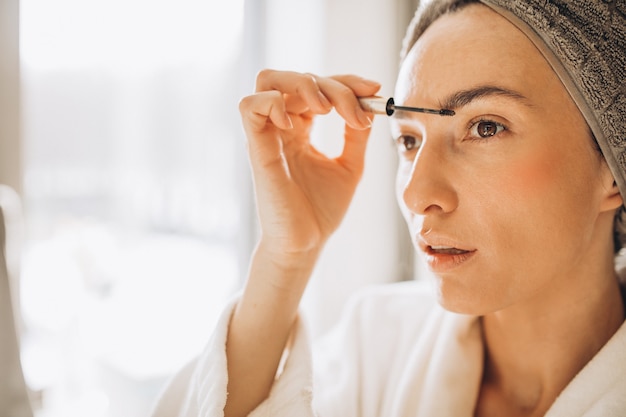 写真 眉毛をブラッシングして鏡を見る若い女性