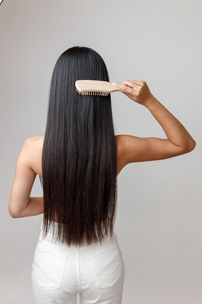 Giovane donna che spazzola i capelli lunghi in studio