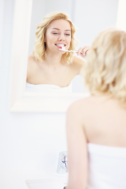 young woman brushing teeth in a bathroom