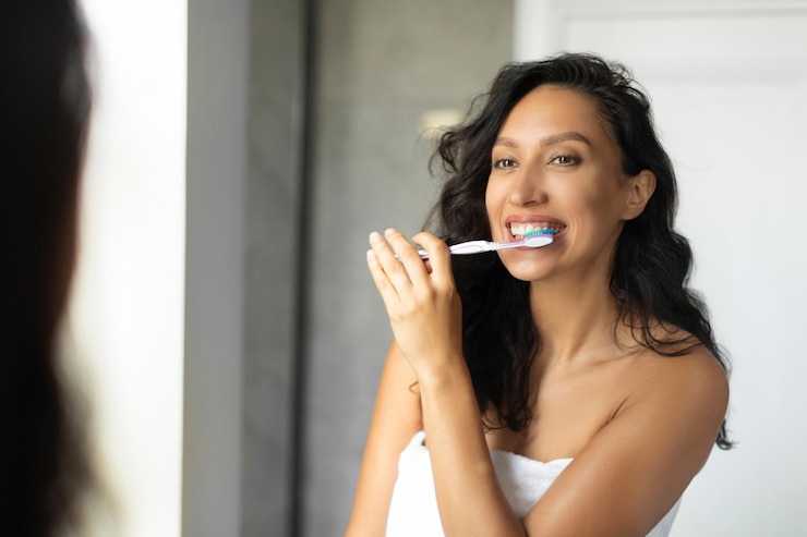 Photo young woman brushing teeth looking at mirror in bathroom daily hygiene routine morning evening