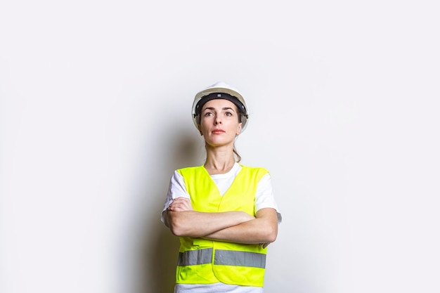 Young woman in building clothes with crossed arms on a light background