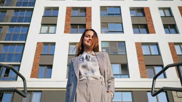 Young woman in a business suit descends the stairs on the background of the building