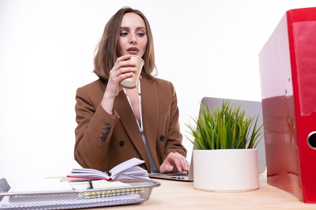 A young woman in a business suit is working on a laptop