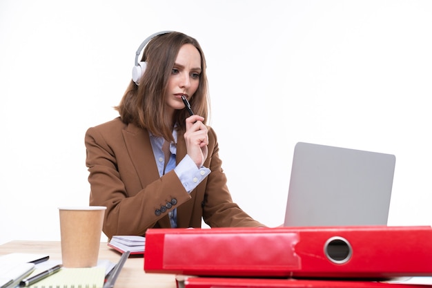 A young woman in a business suit is working on a laptop