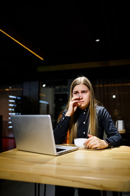 Young woman businessman is sitting at the computer and has a headache from a long working day