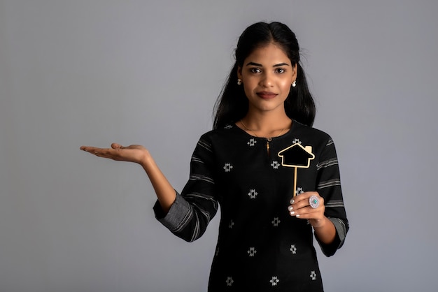 A young woman or businesswoman holding a little cutout board in her hands on a gray wall.