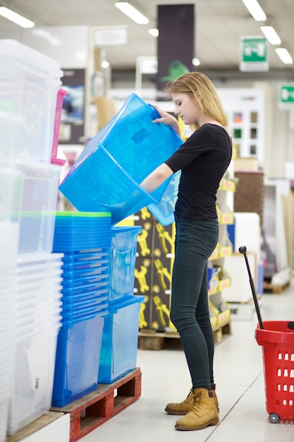 Молодая женщина покупает пластиковые коробки в супермаркете