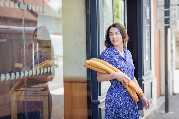 Молодая женщина покупает французский багет