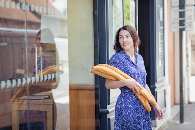 フランスのバゲットを買う若い女性