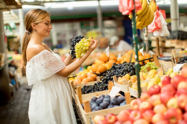 市場で果物を買う若い女性