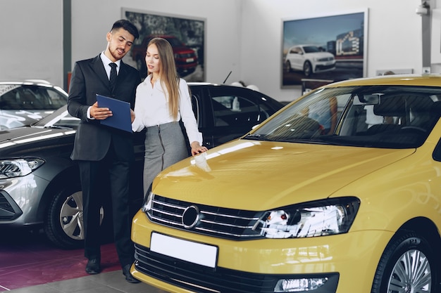 Young woman buying a new car in car salon