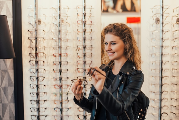 Young woman buying new glasses at optician store.