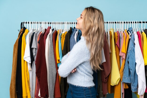 孤立した壁を越えていくつかの服を買う若い女性