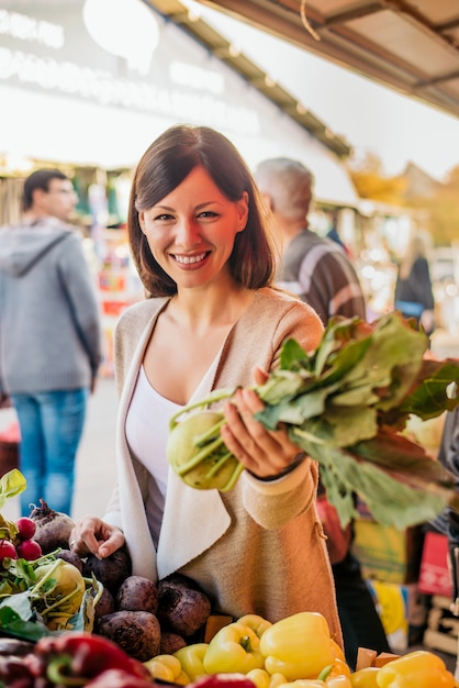 Young woman buying vegetables at the green market.