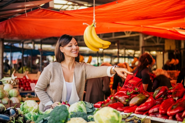 Foto verdure d'acquisto della giovane donna al mercato