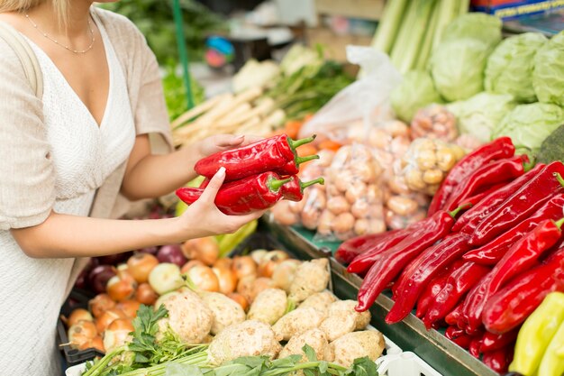 市場で野菜を買う若い女性