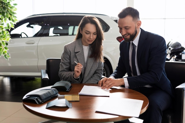 A young woman buys her first car in a car dealership and signs a contract to buy insurance