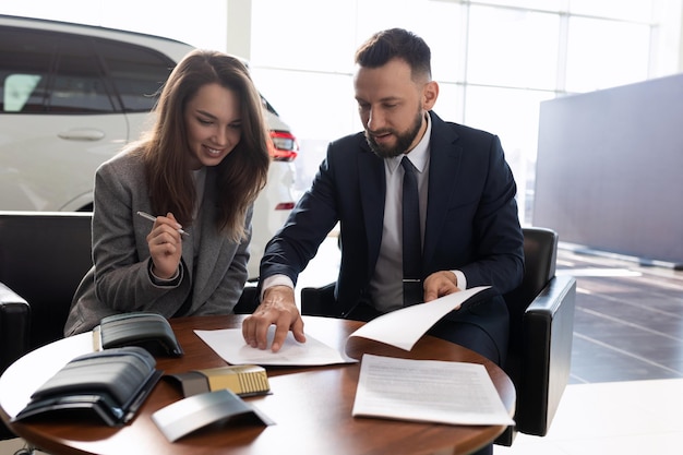 Giovane donna acquista una nuova auto in una concessionaria di auto e firma documenti concetto di assicurazione auto