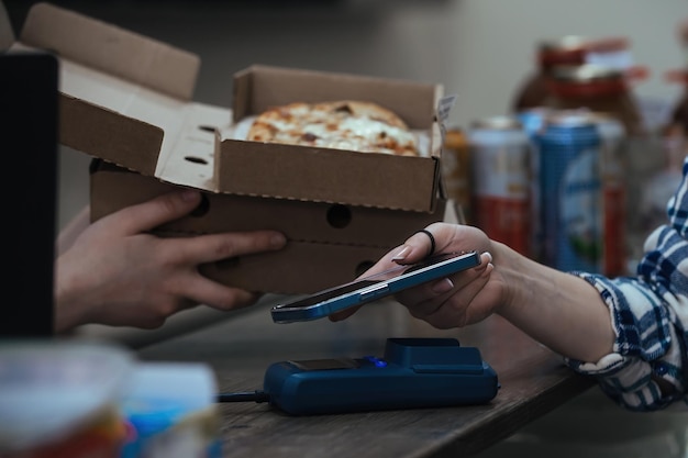 a young woman buys readymade food in cardboard boxes and through a bank terminal